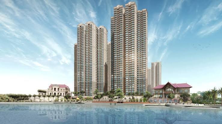 Modern high-rise buildings along a waterfront, with reflections in the water and clear blue skies above.