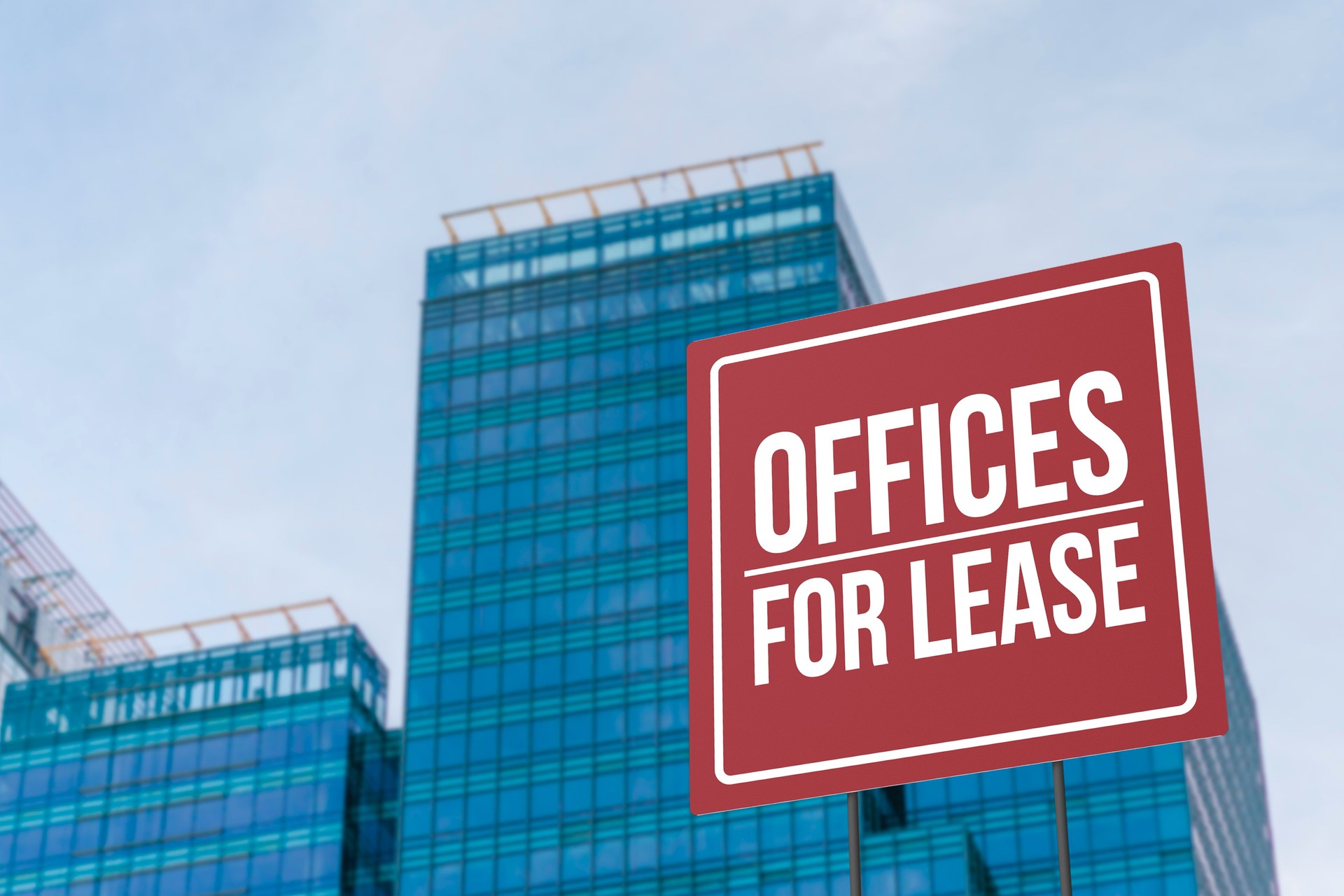 An offices for lease sign in front of a modern glassy commercial Grade A building.